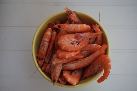 Bowl of cooked shrimp on white background
